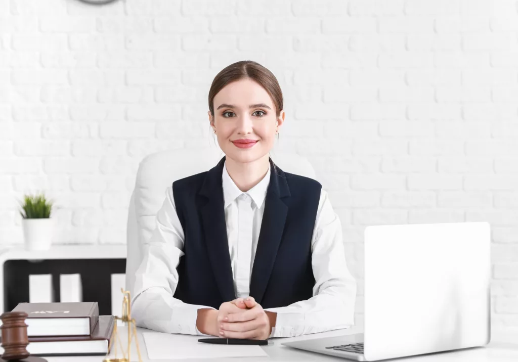 juriste face caméra qui sourit assise à son bureau